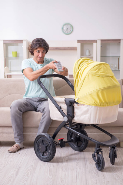 Young man looking after baby in pram - Foto, imagen