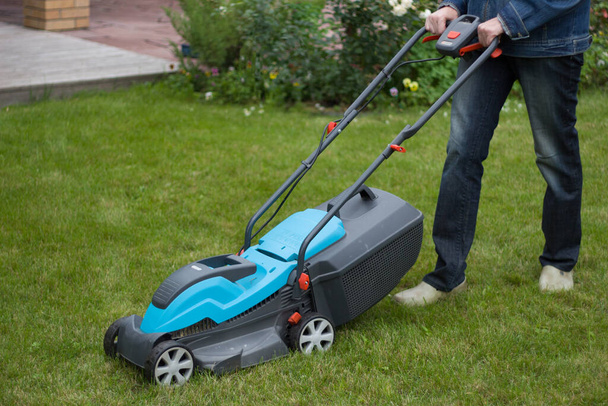 farmer mows grass with a lawn mower.Garden care. - Foto, afbeelding
