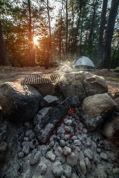 Forest campsite with relaxing fireplace smoke and tent at sunset time - Zdjęcie, obraz