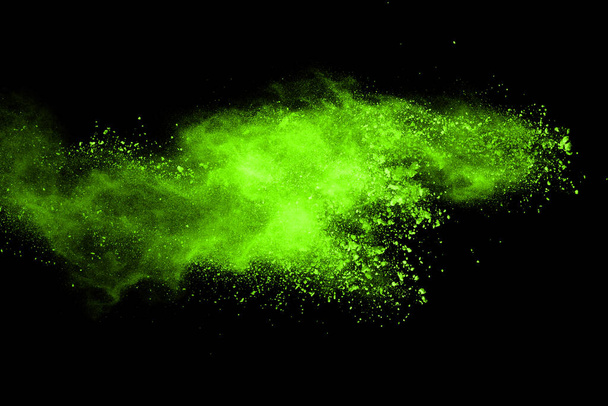 De beweging van abstracte stofexplosie bevroren groen op zwarte achtergrond. Stop de beweging van poedergroen op zwarte achtergrond. Explosief poeder groen op zwarte achtergrond. - Foto, afbeelding