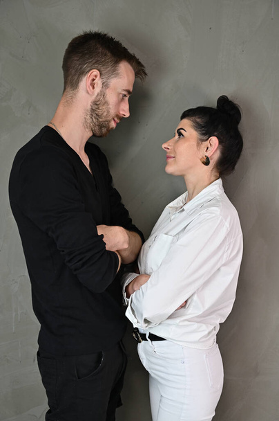 Stylish vertical studio portrait of a caucasian brunette woman and man in a love relationship on a gray background - Foto, imagen