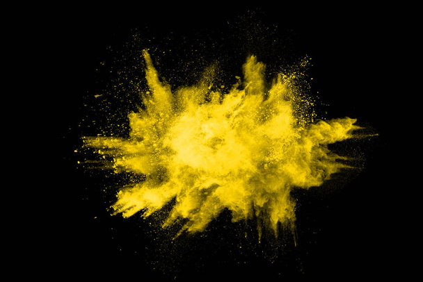 Congelar o movimento da explosão de poeira amarela isolada no fundo preto. - Foto, Imagem