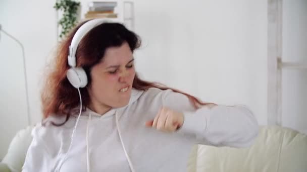 Happy woman listening to music and dancing in living room - Záběry, video