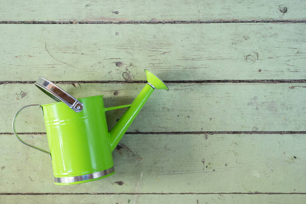 Green watering can on the old wooden garden table background with copy space. - Foto, Imagem