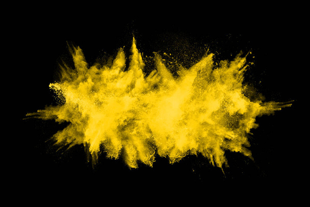 Zamrożenie ruchu eksplozji żółtego pyłu izolowane na czarnym tle. - Zdjęcie, obraz