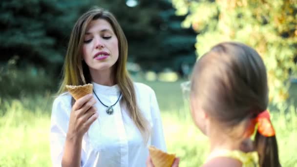 Woman with daughter funny eating ice cream outdoors. Funny children walking. Woman with daughter teenager indulging with ice cream - Záběry, video