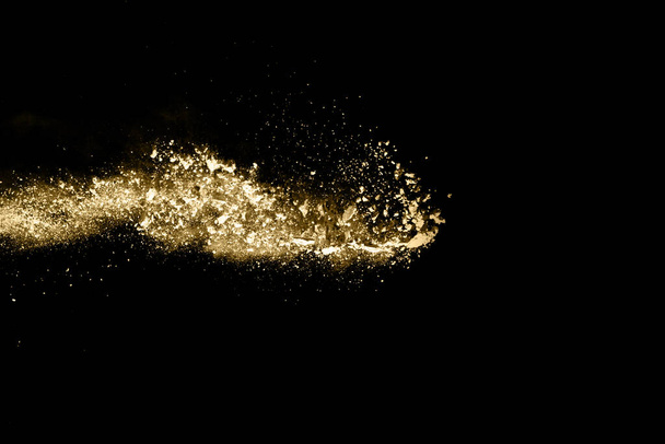 Golden powder explosion on black background. Freeze motion. - Фото, изображение