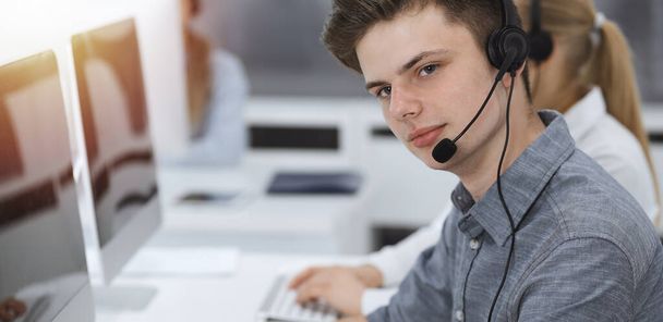 Call center. Group of casual dressed operators at work. Businessman in headset at customer service office. Telesales in business - Fotó, kép