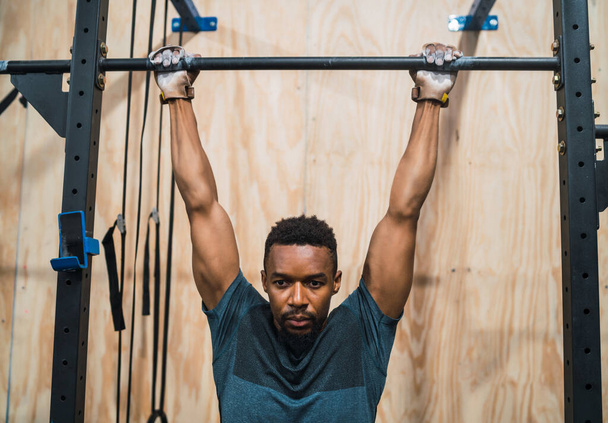Portrait of an athletic man doing pull up exercise at the gym. Sport and healthy lifestyle concept. - Φωτογραφία, εικόνα