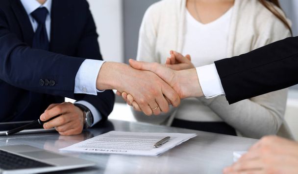 Business people shaking hands after contract signing at the glass desk in modern office. Unknown businessman, male entrepreneur with colleagues at meeting or negotiation. Teamwork, partnership and - Фото, зображення