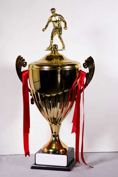 Победитель футбольного турнира большой трофей на белом фоне, золотой кубок футбольный трофей, с красными лентами, турнир
 - Фото, изображение