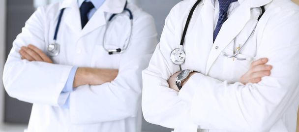Group of modern doctors standing as a team with arms crossed in hospital office, close-up. Physicians ready to examine and help patients. Medical help, insurance in health care, best treatment and - Foto, immagini