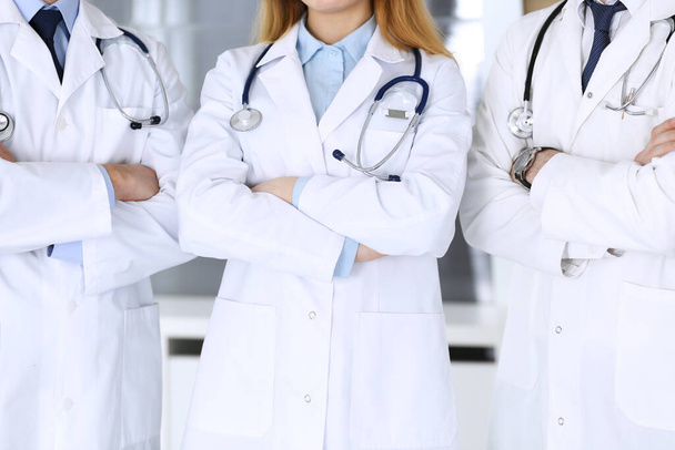 Group of modern doctors standing as a team with arms crossed in hospital office, close-up. Physicians ready to examine and help patients. Medical help, insurance in health care, best treatment and - 写真・画像