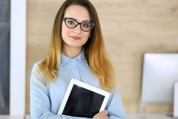Business woman headshot at workplace in modern office. Unknown businesswoman standing straight with tablet computer. Young accountant or secretary looks good - Photo, Image