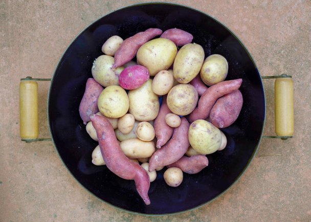 Kırmızı, Yukon ve siyah bir tavada tatlı Japonca da dahil olmak üzere çeşitli patateslerin hemen yukarısından yakın çekim görüntüsü. - Fotoğraf, Görsel