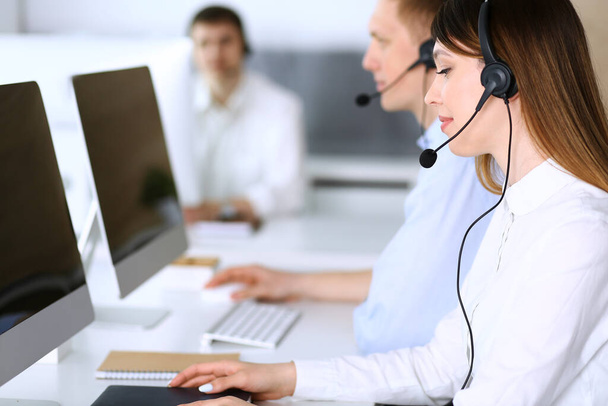 Call center. Group of diverse operators at work. Focus on beautiful asian woman in headset at customer service office. Business concept - Photo, Image