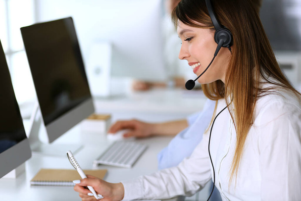 Call center. Group of diverse operators at work. Focus on beautiful asian woman in headset at customer service office. Business concept - Foto, immagini