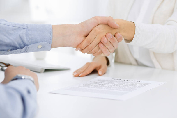 Casual dressed businessman and woman shaking hands after contract signing in white colored office. Handshake concept - Photo, Image