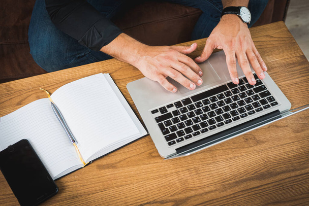 Молодой человек, работающий с ноутбуком, мужские руки на ноутбуке, деловой человек на работе
 - Фото, изображение