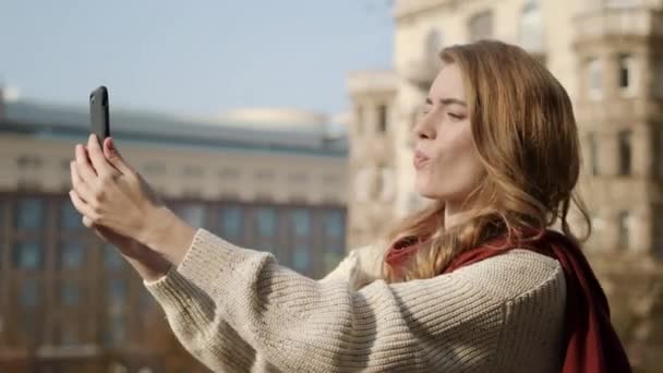 Hübsches Mädchen macht Selfie-Foto im Freien. Lustige Frau benutzt Handy auf der Straße. - Filmmaterial, Video