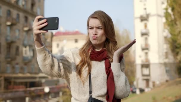 Hipster girl taking selfie outdoors. Flirting woman grimacing for camera - Materiaali, video