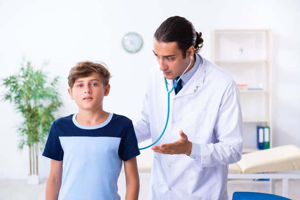 Young male doctor examining boy in the clinic - 写真・画像