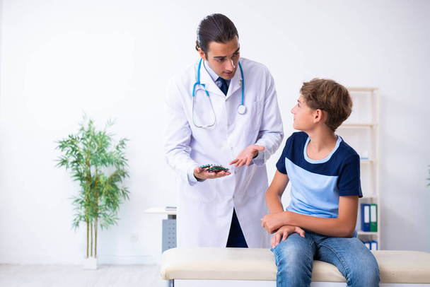 Young male doctor examining boy in the clinic - 写真・画像