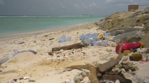 Tyrkysový oceán rozptyluje plastový odpad po bílém písečném pobřeží - Záběry, video