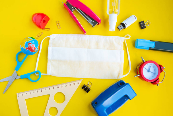 School supplies and medical mask on bright yellow background. Back to school concept. School quarantine concept - Photo, Image