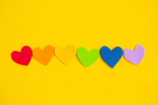 Parlak sarı arkaplanda lgbtq renginde kalpler, üst görünüm, boşluk kopyala - Fotoğraf, Görsel
