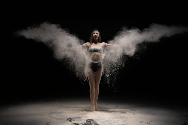 Brunette woman in sportswear throwing sand in air - Фото, изображение
