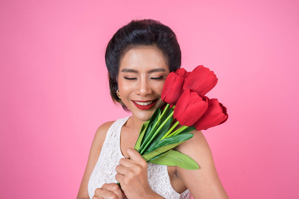 Portrait of Beautiful woman with bouquet of red tulip flowers - Fotó, kép