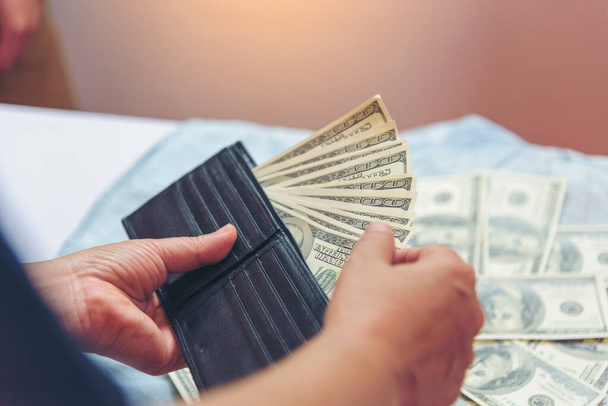 A pénztárcában lévő bankjegy kézben tartása pénzt ad. Férfi kéz mutatja szórt 100 dollár készpénz pénztárca. Megtakarítás Üzletember számolás pénz bankjegy vesztegetés korrupció koncepció. - Fotó, kép