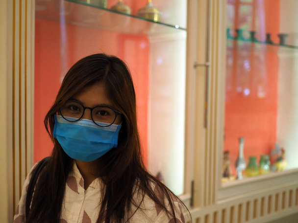 Женщина в защитной маске смотрит на камеру в торговом центре. Новая нормальная концепция. COVID-19 и концепция защиты маски
. - Фото, изображение