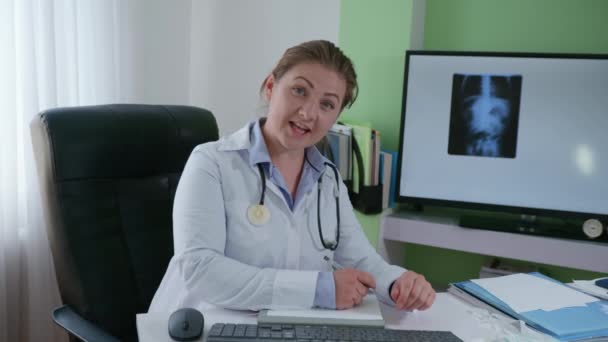 assistenza sanitaria, giovane attraente medico donna con attrezzature mediche consiglia sui pazienti video di comunicazione contro una fotografia a raggi X - Filmati, video