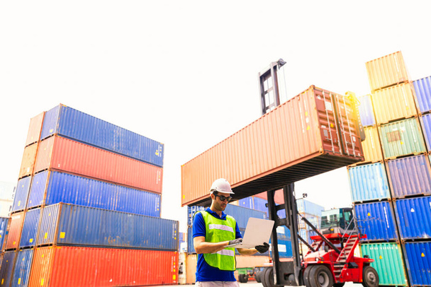 Foreman nebo Operator Objednávka přepravních kontejnerů přes notebook. Foreman se těší na vysokozdvižné vozíky v průmyslové kontejnerové nákladní lodi. - Fotografie, Obrázek