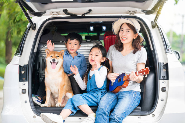 Mutlu Asyalı çocuklar ve Shiba Inu 'lu anne oturuyor ve Sing Song arabada.. - Fotoğraf, Görsel