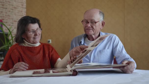 ευτυχισμένη σχέση, ηλικιωμένοι σύζυγοι χαίρονται ανακαλώντας χρόνια που πέρασαν ξεφυλλίζοντας ένα φωτογραφικό άλμπουμ ενώ - Πλάνα, βίντεο