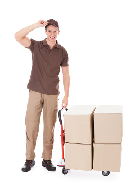 Delivery Man Standing Near Boxes And Hand truck - Foto, Bild