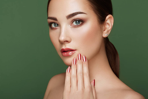 Beauty brunette woman with perfect makeup. Glamour girl. Red lips and nails. Perfect eyebrows. Skin care foundation. Beauty girls face isolated on green background. Fashion photo - Foto, immagini
