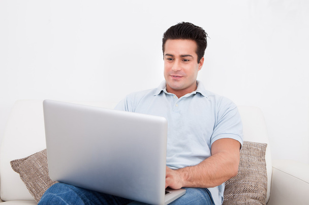 Happy Young Man Sitting On Couch Using Laptop - Photo, Image
