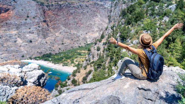 Girl traveler in a hat looks from a cliff at the Oludeniz Butterfly Valley, traveling to Turkey. - Foto, Imagen