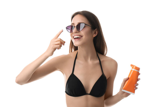 Jonge vrouw die zonnebrandcrème op witte achtergrond aanbrengt - Foto, afbeelding