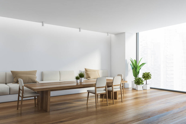 Corner of panoramic dining room with white walls, wooden floor, long table with white chairs and long comfortable sofa with beige cushions. Window with blurry cityscape. 3d rendering - Foto, imagen