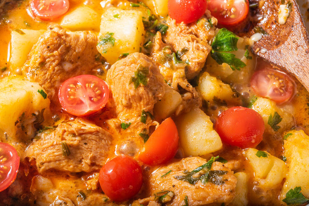 Cooking potatoes with chicken in a hot sauce, Italian cuisine - Arrabbiata garlic chicken with potatoes is cooked in a pan, close-up - Photo, Image