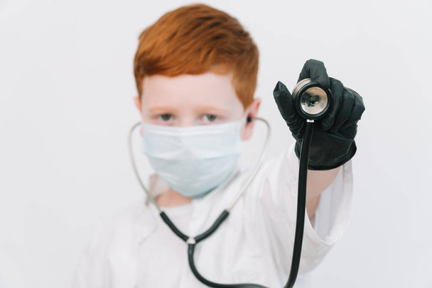 Close up of caucasian littile doctor with a stethoscope in protective mask - Photo, image