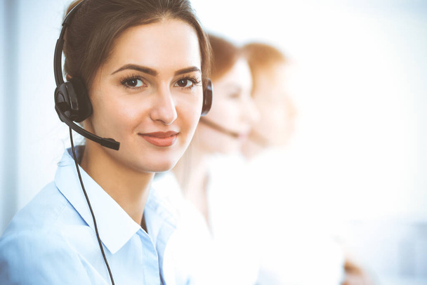 Call center operators. Focus on beautiful business woman using headset - Foto, afbeelding