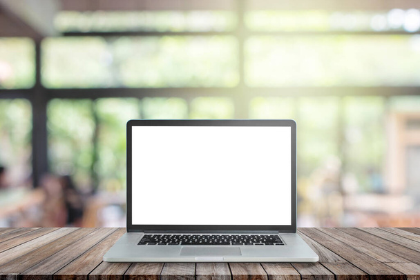 Usato computer portatile nero con schermo bianco vuoto su tavolo di legno e immagine sfocata di caffetteria o ristorante caffè in background. - Foto, immagini