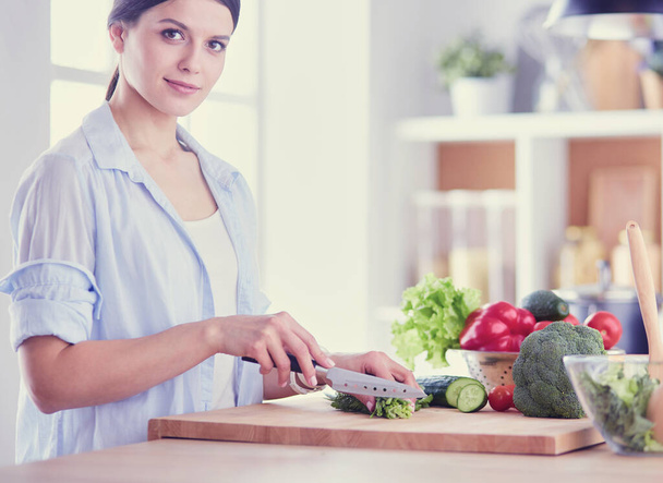 Fiatal nő vágás zöldségek a konyhában otthon. - Fotó, kép