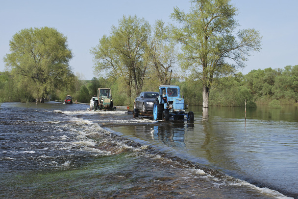 Überschwemmungen, überflutete Straße Traktor trägt Autos. - Foto, Bild
